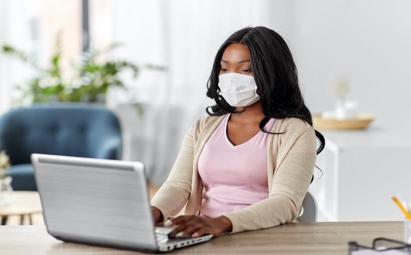 woman in mask with laptop working at home office