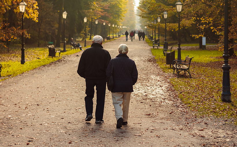 Elderly couple walking in park in autumn