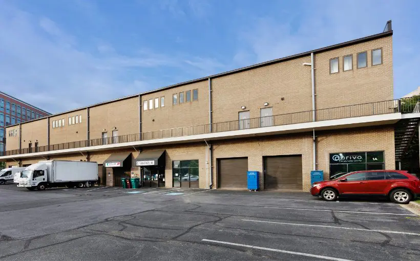 Exterior view of single-story industrial building with truck-loading docks and shop entrances.