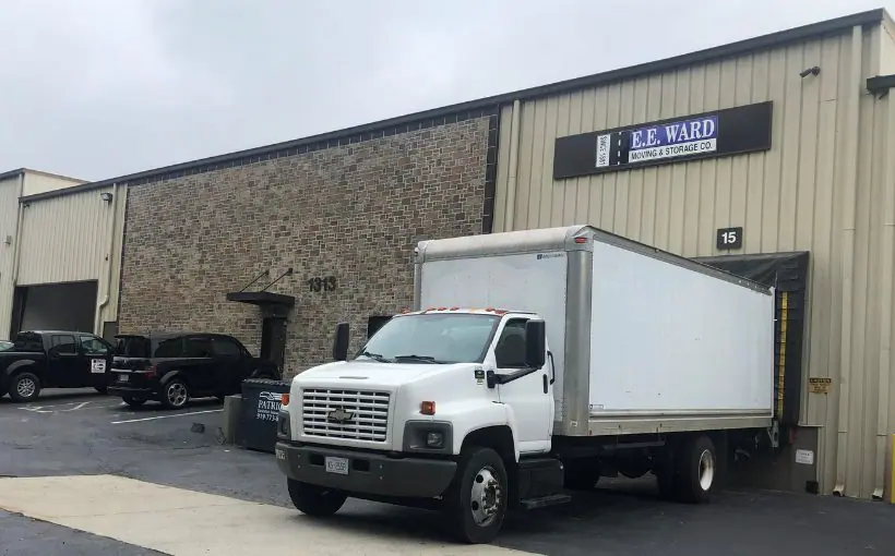 Exterior image of a single-story industrial building with a moving truck backed into a loading dock.