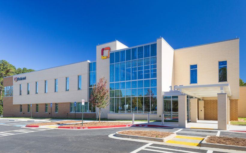 Front exterior view of a two-story concrete medical office building with top-to-bottom windows in the center and cover for patient drop-off and pick-up