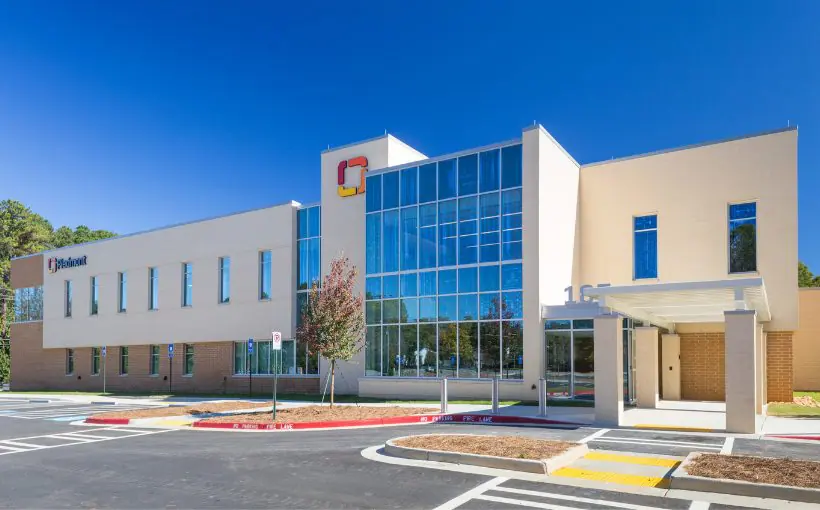 Front exterior view of a two-story concrete medical office building with top-to-bottom windows in the center and cover for patient drop-off and pick-up