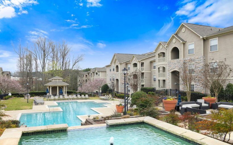 Exterior view of three-story apartment complex surrounding pools and lounging area