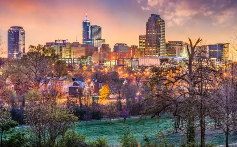 City skyline view of downtown Raleigh high-rise buildings facing a park at twilight