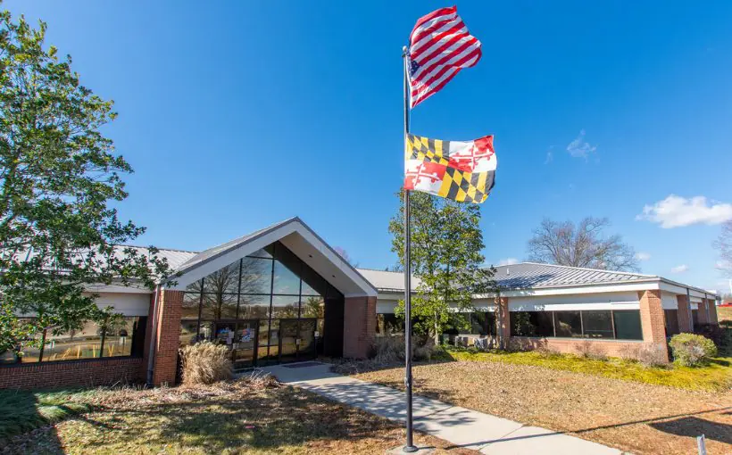 Exterior view of a brick single story building with a glass fronted entrance and peaked roof