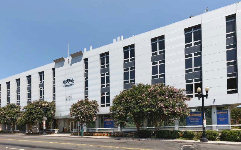 Exterior streetside view of a mid rise concrete and windows office building
