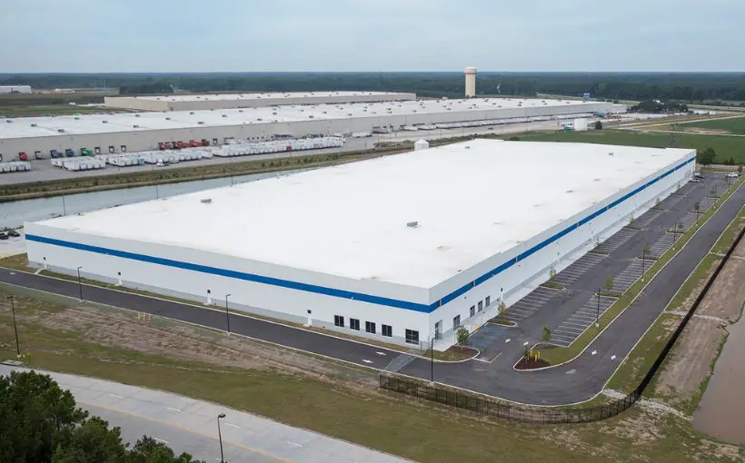 Aerial view of the roof of a single-story rectangular warehouse building and surrounding driveways