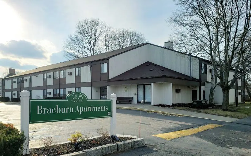 Exterior view of a two-story building with outside unit entrances, and welcome sign