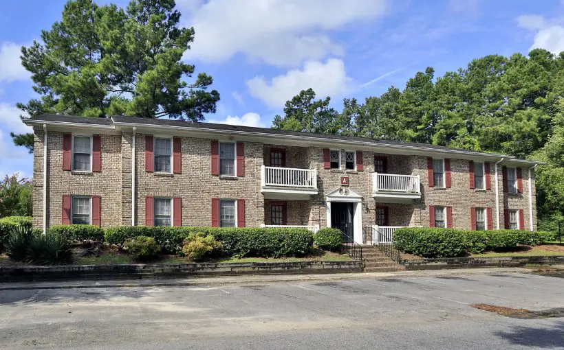 Front exterior view of a two-story brick apartment building facing the parking lot and with a central entrance door