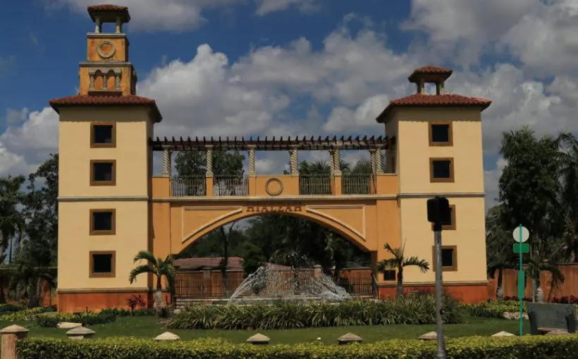 City welcome structure resembling a Spanish style covered bridge with columns behind a large circular fountain