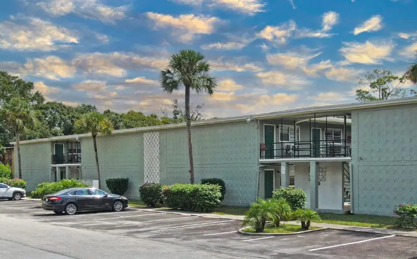 Exterior image of a two story concrete apartment building with a flat roof and outside entrances facing a courtyard