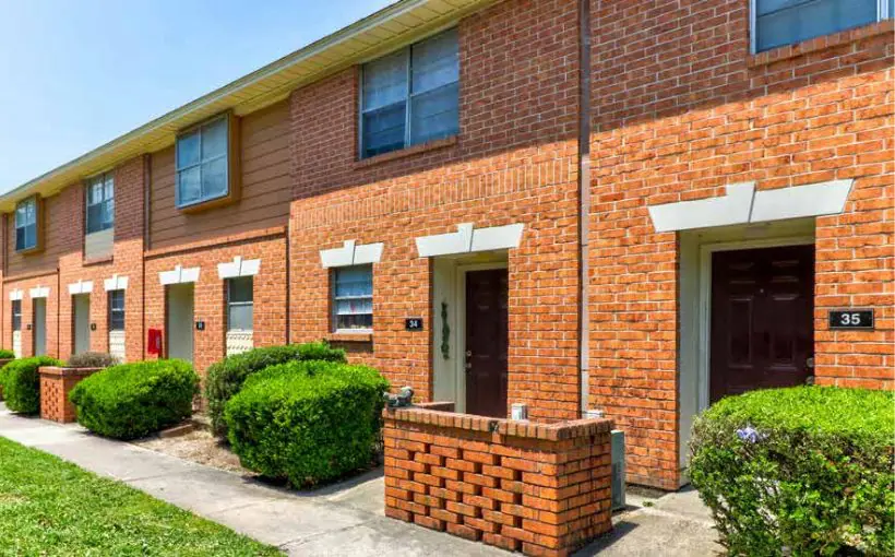 Exterior view of two-story brick apartment building with unit entrances from the outside
