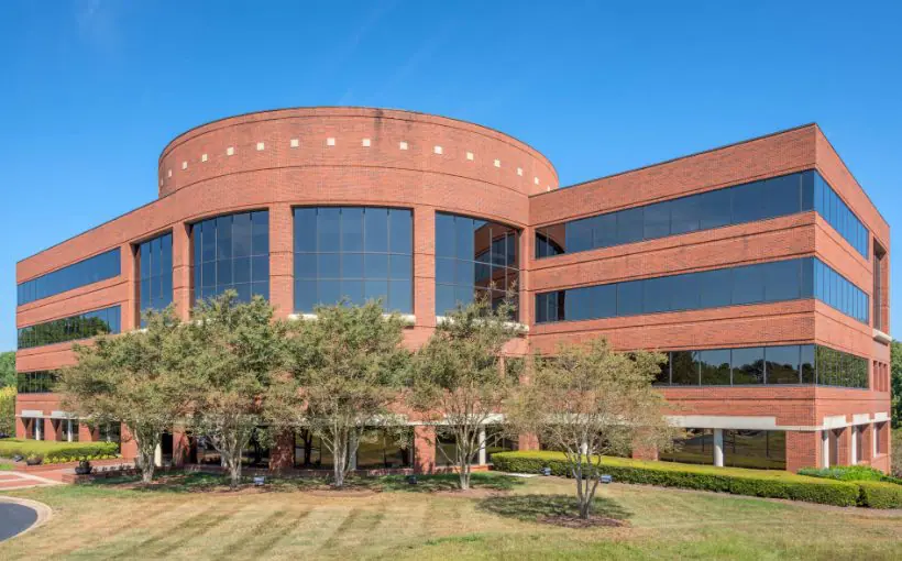 Front ground-level exterior view of brick office building with central window-filled rotunda