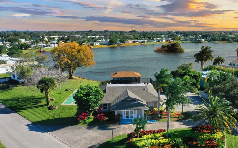 Aerial view of a waterfront mobile home community with community center building at the entrance