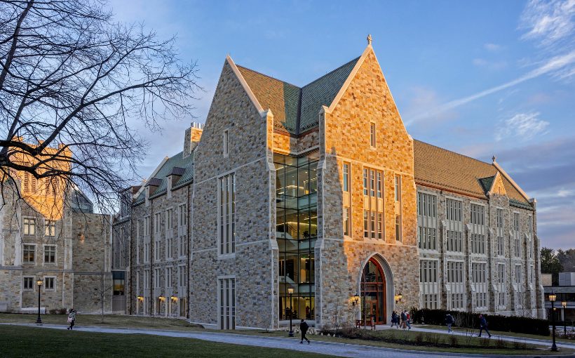 Stone and windows multi-story building with peaked roofline and entrance resembling that of a cathedral