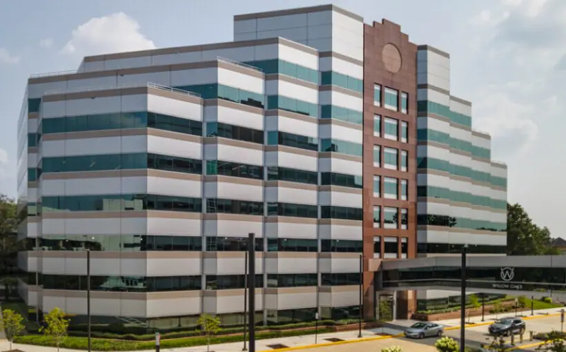 Front exterior view of mid-rise office building with covered walkway leading to parking deck